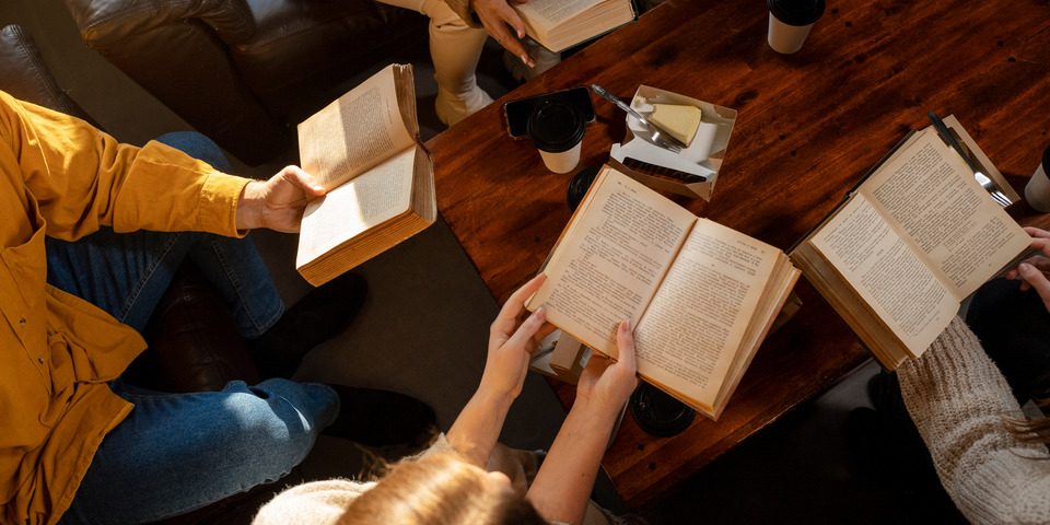 Widok na ludzkie ręce trzymające książki nad stołem